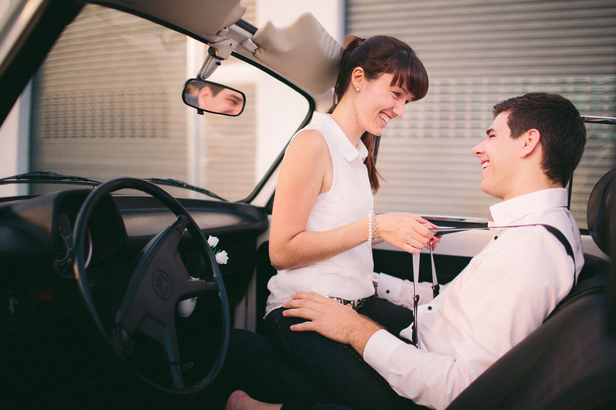 Paar sitzt in VW Käfter Cabrio, beide lachen