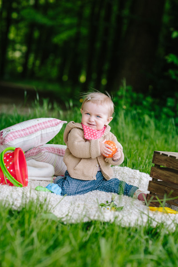 Kind sitzt auf Fell im Wald und spielt