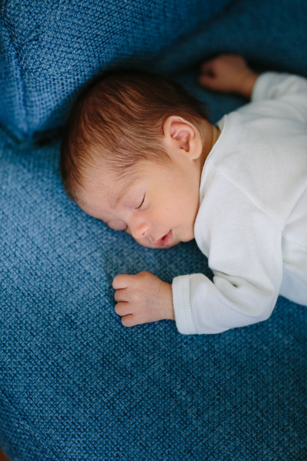 Baby liegt auf blauem Sessel