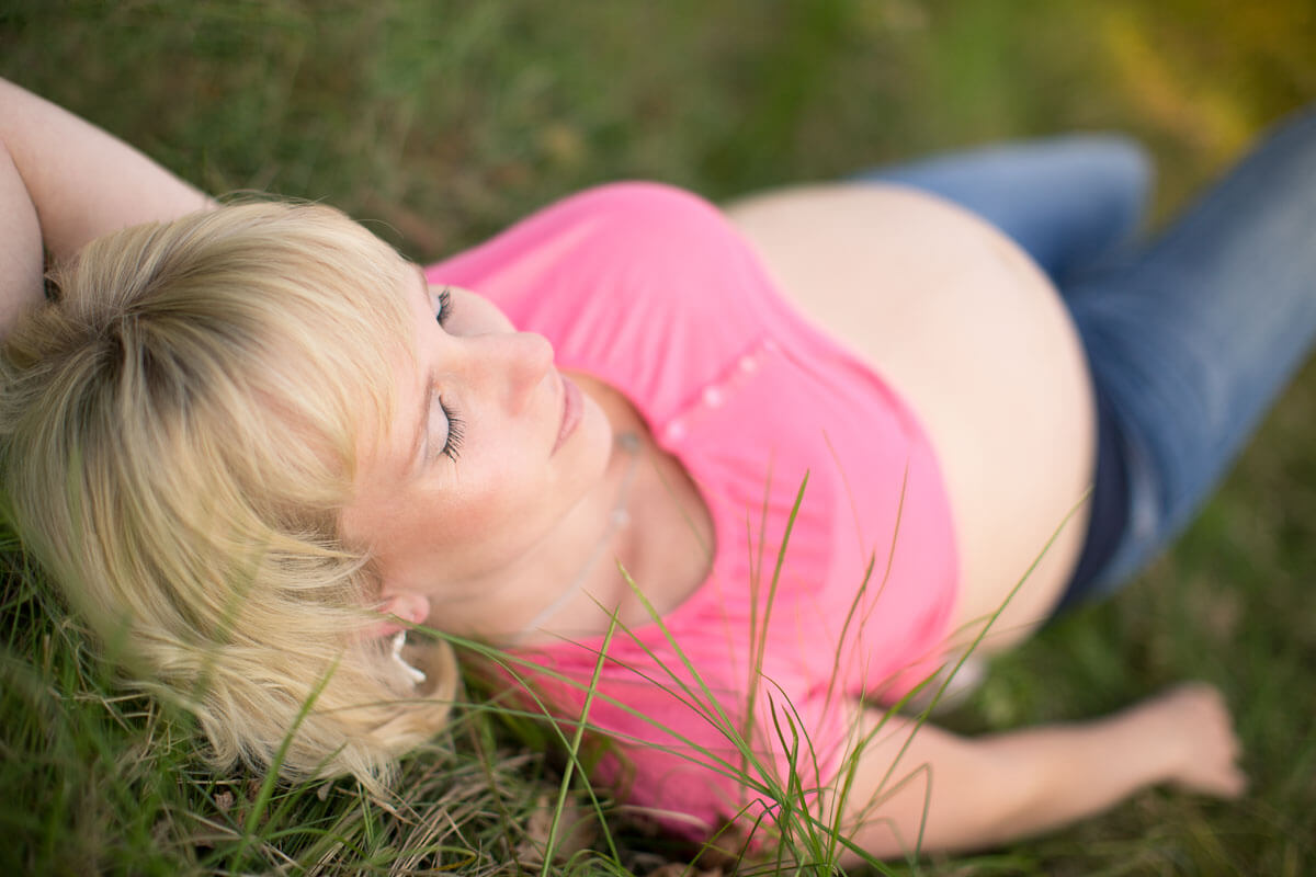 Schwangere Frau liegt im Gras